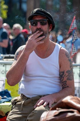 September 26, 2026, London, United Kingdom: An attendee at the King™s Cross Classic Car Boot Sale in London wears a flat cap and white vest while smoking a cigarette. The Kings Cross Classic Car Boot Sale returned to Granary Square and Stable Street, King™s Cross, London, for its 11th year. Held several times throughout the year, the event brings together vintage fashion, second-hand clothing, jewellery, homewares, collectables and vinyl records alongside classic cars, motorcycles and commercial vehicles. Visitors browsed stalls and traders, with many making a special effort to dress in period clothing inspired by the 1950s, 1960s and 1970s.continuing a tradition associated with the event. London United Kingdom - ZUMAs197 20260926_aaa_s197_386 Copyright: xJamesxWilloughbyx