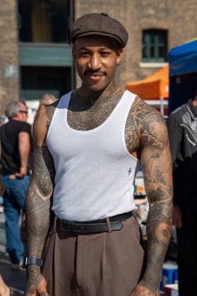 September 26, 2026, London, United Kingdom: An attendee at the King™s Cross Classic Car Boot Sale in London wears a flat cap and white vest. The Kings Cross Classic Car Boot Sale returned to Granary Square and Stable Street, King™s Cross, London, for its 11th year. Held several times throughout the year, the event brings together vintage fashion, second-hand clothing, jewellery, homewares, collectables and vinyl records alongside classic cars, motorcycles and commercial vehicles. Visitors browsed stalls and traders, with many making a special effort to dress in period clothing inspired by the 1950s, 1960s and 1970s.continuing a tradition associated with the event. London United Kingdom - ZUMAs197 20260926_aaa_s197_378 Copyright: xJamesxWilloughbyx