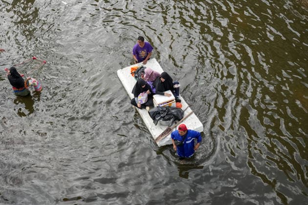 Severe floods in Bang Kapi District, Bangkok - 28 Sept 2026 Men pushing a large piece of polystyrene through the floodwater, carrying three women with bags of food supplies along the flooded street on Lat Phrao Road in Bang Kapi District. On September 26, all 50 districts of Bangkok were declared disaster-affected areas. Three days later, floodwaters still remained in parts of the city. In heavily affected areas such as Bang Kapi District, residents remained in floodwater. Bangkok Thailand Copyright: xNathaliexJamoisx xSOPAxImagesx NathalieJamois_BangKapiFlood2026-16