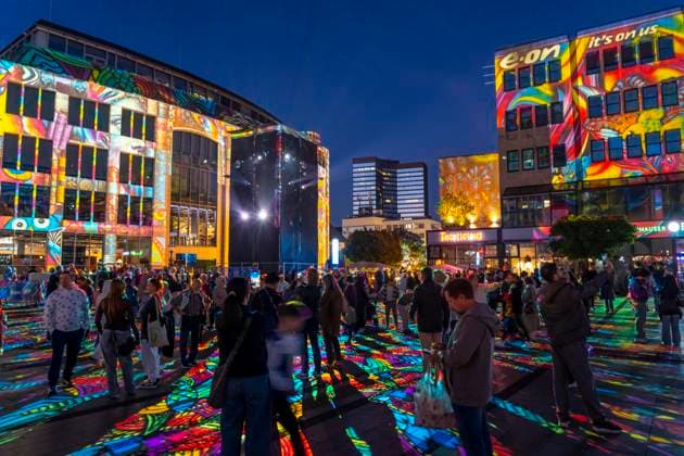 Essen Light Festival, in the city center; the light installation Diving in the Sea of Colors by Berlin-based artist Daniel Margraf illuminates the buildings on the large Kennedy Platz; visitors become part of the light art installation; North Rhine-Westphalia, Germany; Essen Light Festival