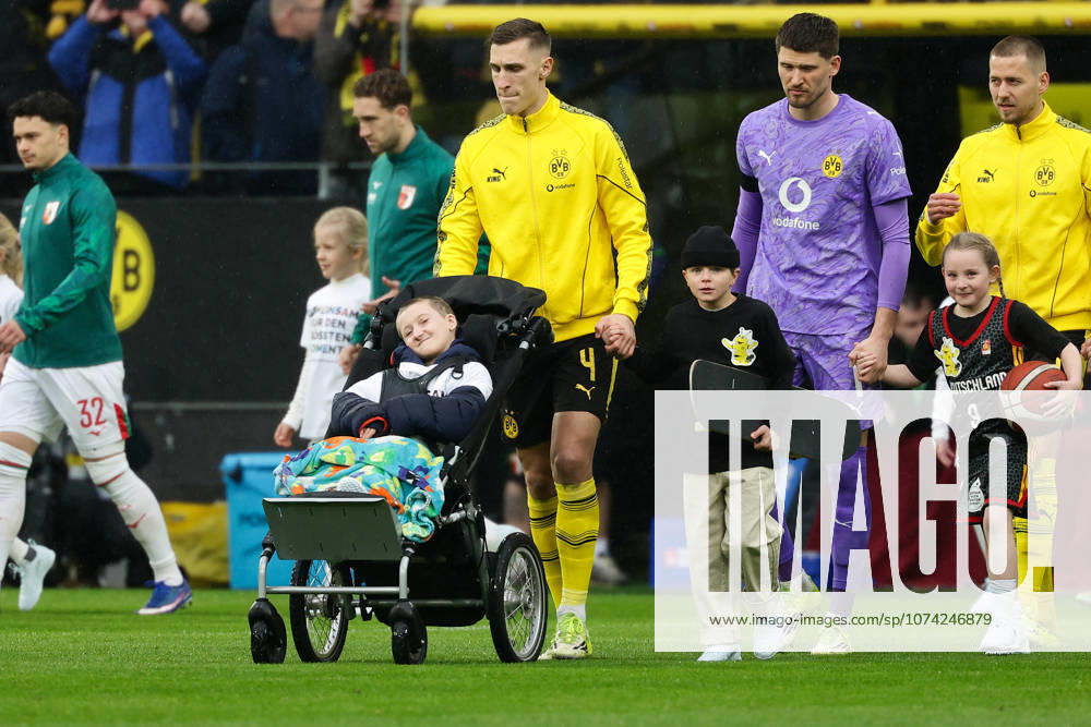 Dortmund, Germany, 14 03 26, Nico Schlotterbeck Borussia Dortmund with a child during the Bundesliga 1 match between Borussia Dortmund FC Augsburg at Signal Iduna Park in Dortmund Photo by Joachim Bywaletz DFB DFL REGULATIONS PROHIBIT ANY USE OF PHOTOGRAPHS AS IMAGE SEQUENCES AND OR QUASI VIDEO