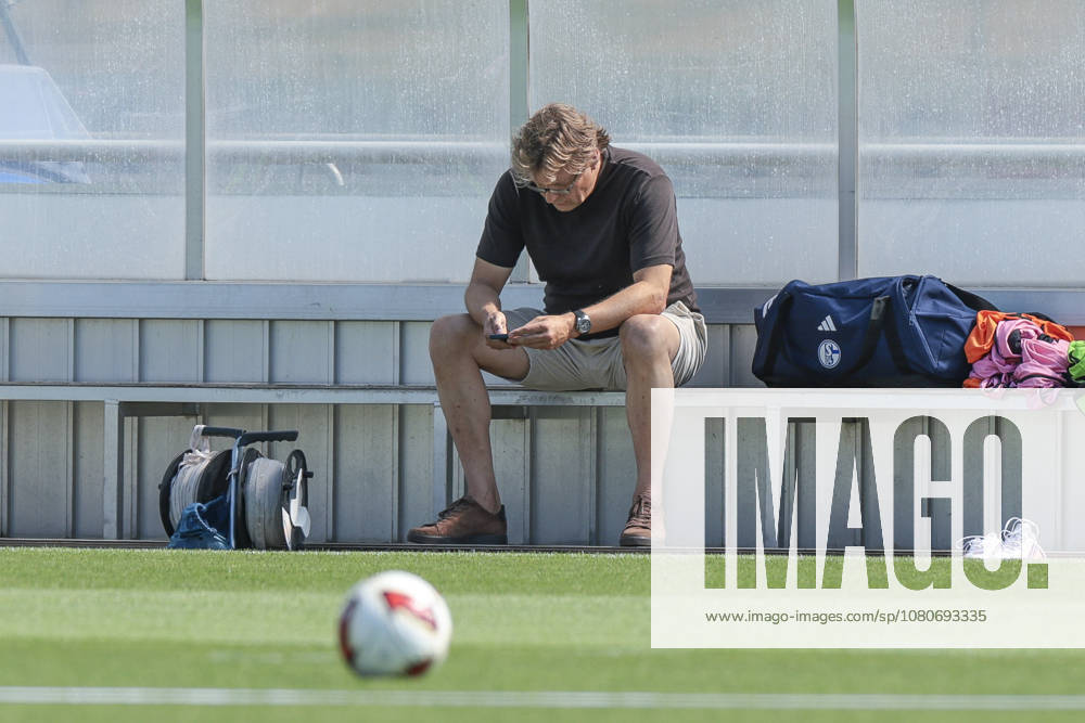 Soccer, FC Schalke 04 Training Session; Youri Mulder, Director of Professional Soccer at FC Schalke 04, looks at his smartphone; Gelsenkirchen, FC Schalke 04 Training Facility, North Rhine-Westphalia, Germany; xRHR PHOTO YYx