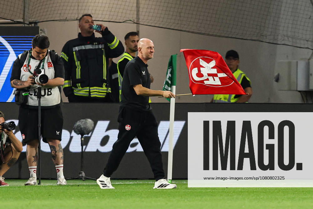 Coach Torsten Lieberknecht of 1. FC Kaiserslautern holding a 1. FC Kaiserslautern flag after the final whistle of the 2026–2027 Bundesliga match between VfL Wolfsburg and 1. FC Kaiserslautern at the Volkswagen Arena in Wolfsburg. Soccer, Man,Men, Germany