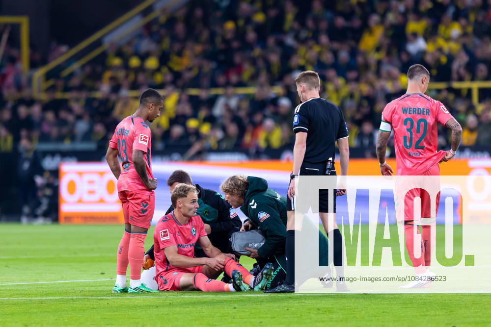 Dortmund, Germany, October 9, 2026, Bundesliga 1, 2026–2027, Matchday 5: Borussia Dortmund vs. SV Werder Bremen. Pictured: Amos Pieper (SVW) sits on the ground injured; from left: Arthur (SVW), Amos Pieper (SVW), referee Christian Dingert, Marco Friedl (SVW). DFL and DFB regulations prohibit any use of photographs as image sequences and or quasi-video. Signal Iduna Park, North Rhine-Westphalia