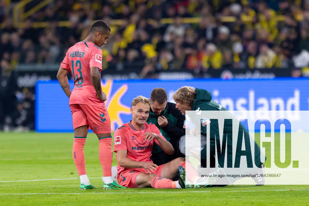 Dortmund, Germany, October 9, 2026, Bundesliga 1, 2026–2027, Matchday 5: Borussia Dortmund vs. SV Werder Bremen. Pictured: Amos Pieper (SVW) sits on the ground injured; from left: Arthur (SVW), Amos Pieper (SVW). DFL and DFB regulations prohibit any use of photographs as image sequences and or quasi-video. Signal Iduna Park, North Rhine-Westphalia