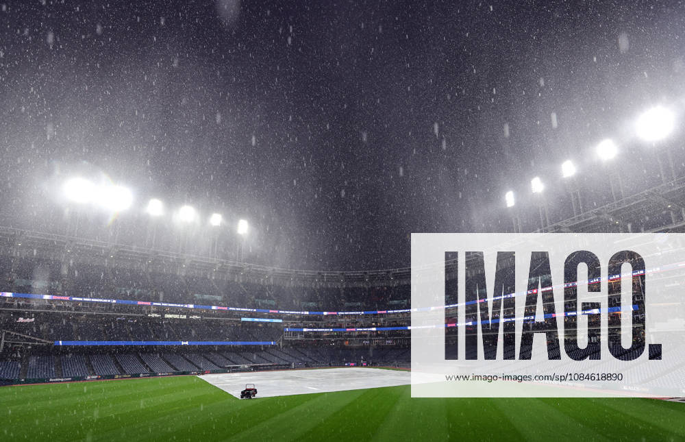 A tarp covers the infield as a heavy rain falls before the start of game four of the MLB, Baseball Herren, USA American League Championship Series between the Tampa Bay Rays and the Cleveland Guardians at Progressive Field in Cleveland, Ohio, on Friday, October 16, 2026. The 8pm ET start of the game has been delayed due to the weather. CLE20261016703 AARONxJOSEFCZYK