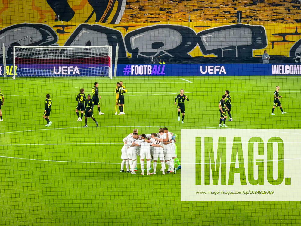 Germany, Soccer, 2026–2027 UEFA Champions League, Matchday 3, VfB Stuttgart vs. Atlético Madrid, October 20, 2026, Stuttgart Arena, Stuttgart: VfB Stuttgart team huddle before the game, Atlético Madrid players in the background; sports venue, interior view, wide shot, behind-the-goal perspective, team, team spirit, motivation, pregame preparation, soccer, playing field, goal net, fan choreography, Cannstatter Kurve, fans, UEFA, perimeter advertising, floodlights, Champions League