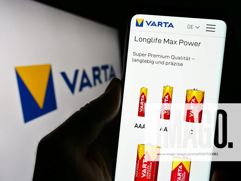 Person holding cellphone with webpage of German battery company Varta AG on screen. Stuttgart, Germany - 09-11-2023: Person holding cellphone with webpage of German battery company Varta AG on screen in front of business logo. Focus on center of phone display.
