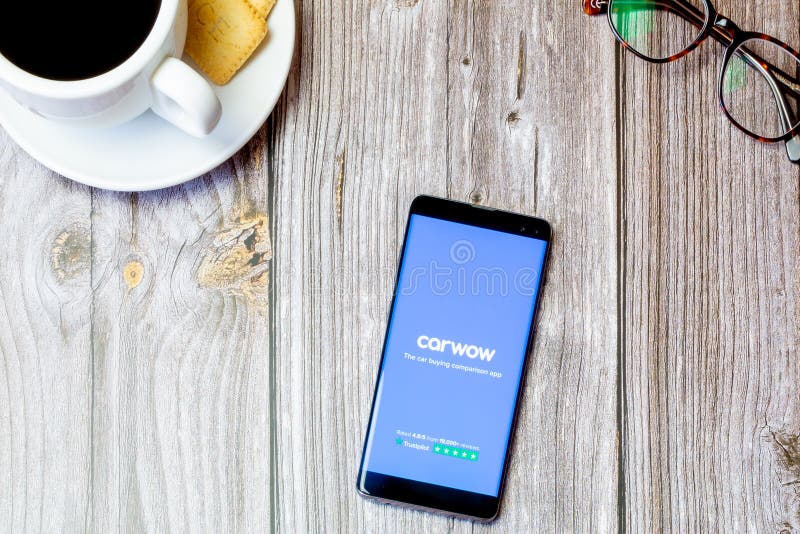 Portsmouth, Hampshire, UK A mobile phone or cell phone laid on a wooden table with the Carwow app open on screen, 03-22-2021 Portsmouth, Hampshire, UK A mobile phone or cell phone laid on a wooden table with the Carwow app open on screen