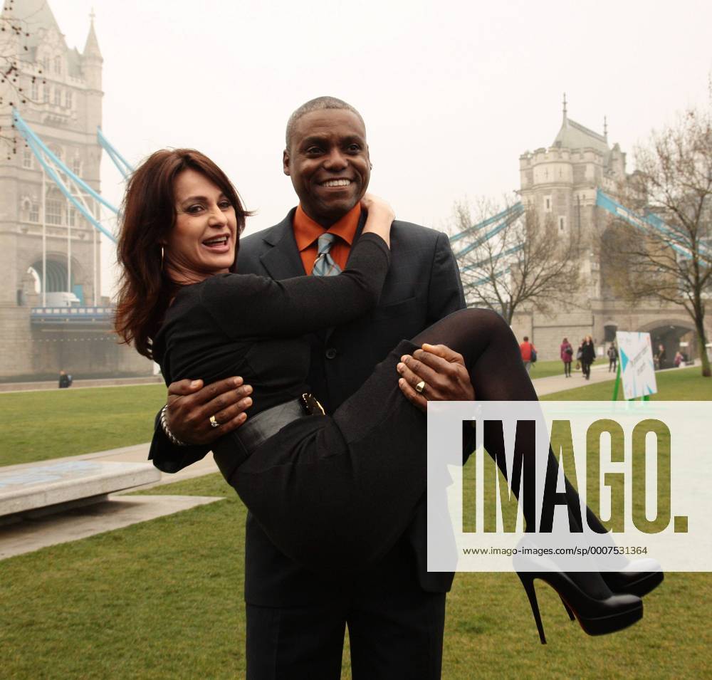 Carl Lewis (USA) lifts up Romanian Nadia Comaneci at a photocall to launch the London 2012 Olympics tickets going on sale today at City Hall, London - LON2011031502 o0 Verkauf Ticket Karten Eintrittskarten
