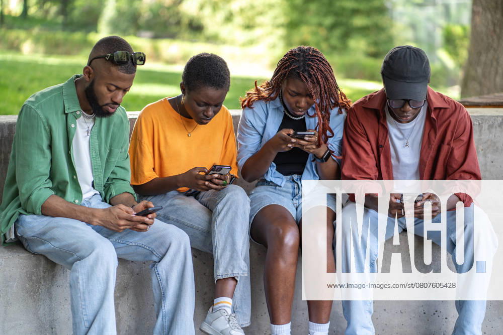 Black guys in park hang in smartphones, browse social media, chatting. Youth dependency on gadgets Black guys in park hang in smartphones, browse social media, chatting. Youth dependency on gadgets ,model released, Symbolfoto