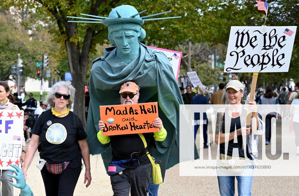 WASHINGTON, DC - OCTOBER 18: Demonstrators holding signs take to the streets during a nationwide No Kings rally against President Donald Trump s administration on October 18, 2025 in Washington, DC.