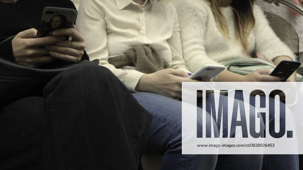 Nahaufnahme einer Frau, die in der U-Bahn am Telefon sitzt. Medien. Menschen, die in der U-Bahn fahren, benutzen Smartphones. Smartphone-Sucht in der U-Bahn Close-up of woman sitting in phones in subway. Media. People riding in subway use smartphones. Smartphone addiction in metro. (License=RM)