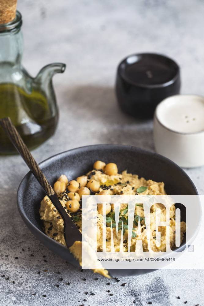 Kichererbsenhummus in der schwarzen Schale, dekoriert mit Sesamsamen und Kichererbsengrün. Vegane Rezepte, Gerichte auf pflanzlicher Basis. Konzept für umweltfreundliches Wohnen. Biologische Lebensmittel. Vegetarische Küche Chickpeas hummus in the black bowl decorated with sesame seeds and chickpeas greens. Vegan recipes, plant-based dishes. Green living concept. Organic food. Vegetarian cuisine
