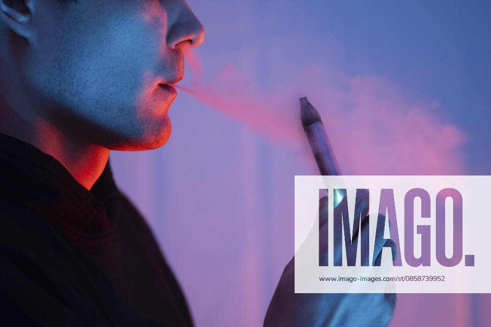 Nahaufnahme eines Mannes, der eine elektronische Zigarette raucht. farbiges Licht Close-up of a man smoking an electronic cigarette. colored light