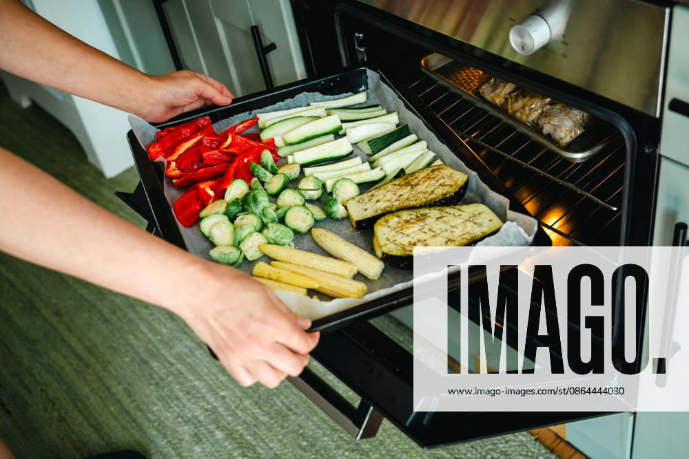 Placing a colorful tray of vegetables into the oven Corby, England, United Kingdom R_ATMT260818-2108729-01 ,model released, Symbolfoto ,property released