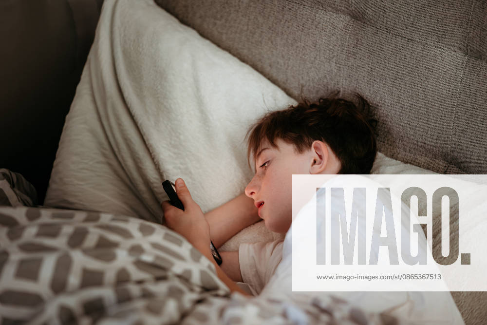 Young boy scrolling on his phone in bed Boise, Idaho, United States CR_PHZD2608291A-2107944-01 ,model released, Symbolfoto ,property released