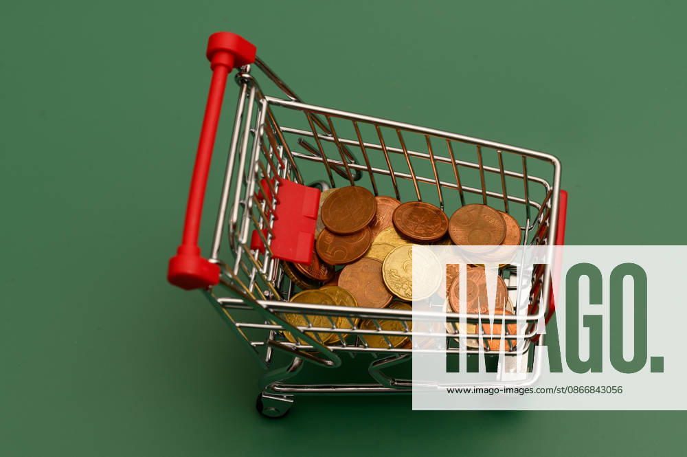 Mini shopping cart with coins seen from above, Waldsee, Germany, September 14, 2026. Top view of a mini shopping cart with Euro coins on a green background. Stock image representing loose change, saving, and household budget.