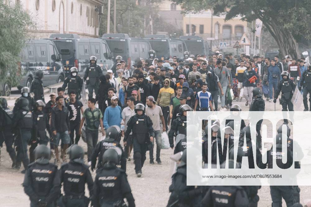 Dozens of young migrants walk escorted by riot police officers during the eviction of the makeshift camp on El Trampolin beach in Ceuta. Spanish National Police began evicting the makeshift camp on El Trampolin beach in Ceuta on October 4, where more than 3,000 migrants, most of them young Moroccan men, were living. Dozens of police vans, armoured vehicles of the Police Intervention Units (UIP), drones and boats took part in the operation. People were taken by bus to the temporary centre at the Tarajal border to be identified, and the authorities plan to clear the beach in phases before October 15. The camp grew after a mass arrival at the end of July 2026 set off a migration and political crisis. Ceut - ZUMAs392 20261004_zip_s392_044