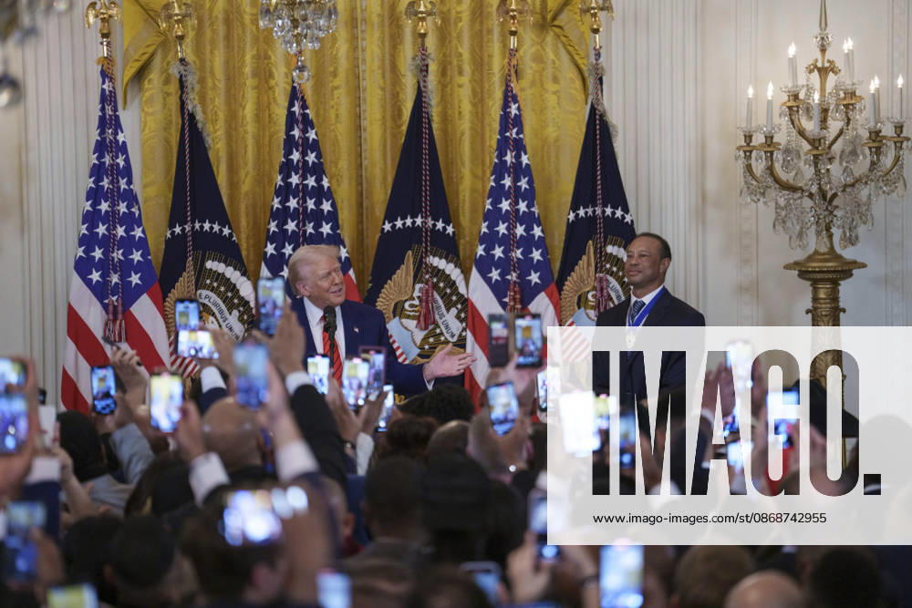 Guests take photos using their phones as U.S. President Donald Trump and golfer Tiger Woods appear at a reception honoring Black History Month in the East Room of the White House, February 20, 2025 in Washington, D.C. Trump introduced golfer Tiger Woods as a surprise guest at the reception in the East Room, where he praised Woods as one of the greatest athletes of all time. Washington United States of America - ZUMAp138 20261006_zaa_p138_008