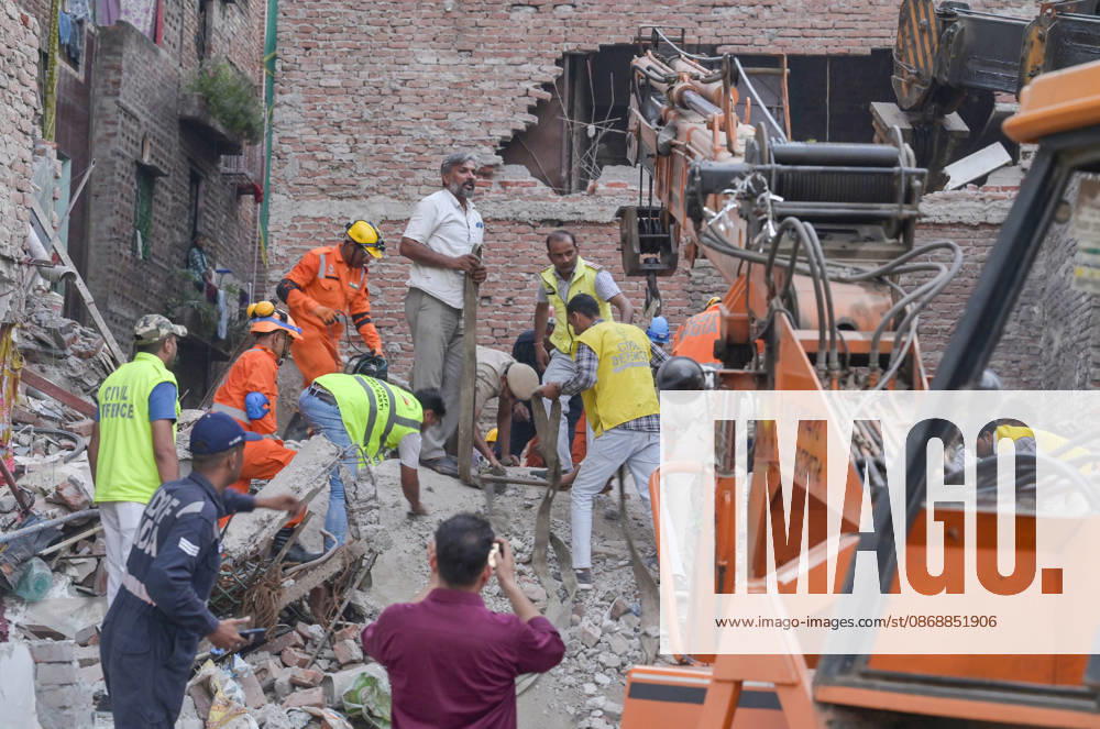National Disaster Response Force (NDRF) jawans, Delhi Fire Service personnel, and local residents navigate heavy rubble during a search and rescue operation after a four-storey residential building collapsed in the New Seemapuri area of Shahdara on October 7, 2026, in New Delhi, India. The structural collapse occurred around 3:30 PM behind the local fish market, trapping multiple residents under concrete slabs and damaging two adjoining houses. At least one minor died while eight people were rescued and rushed to Rajiv Gandhi Super Speciality Hospital for emergency medical treatment as sniffer dogs and excavators worked late into the evening to locate remaining trapped survivors. (Photo by Raj K Raj Hindustan T