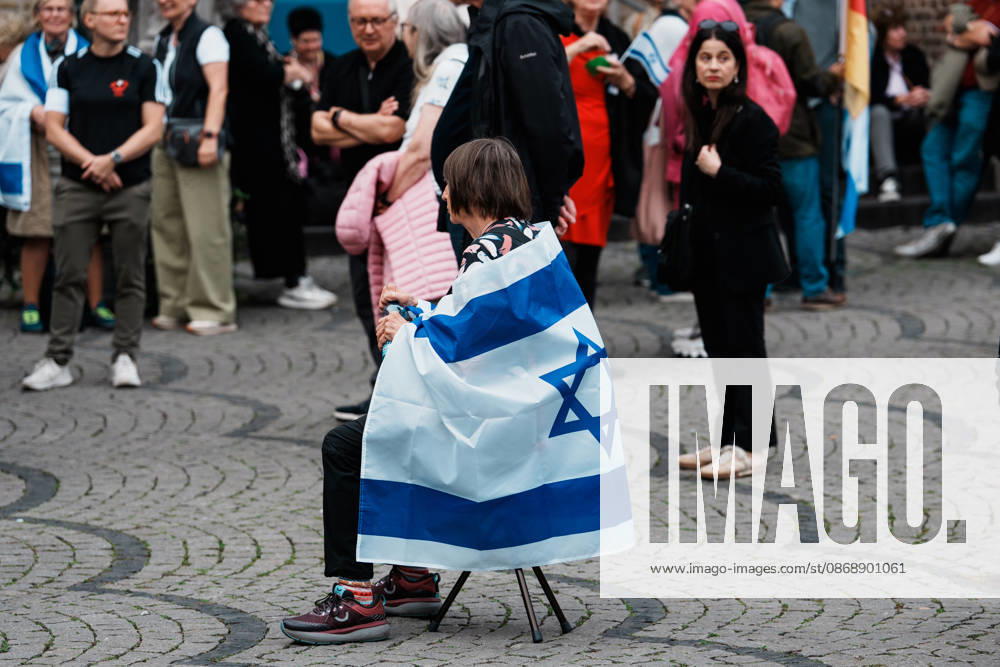 Rally in Düsseldorf marking the anniversary of Hamas s terrorist attack on Israel on October 7, 2023, and protesting anti-Semitism; woman holding a flag