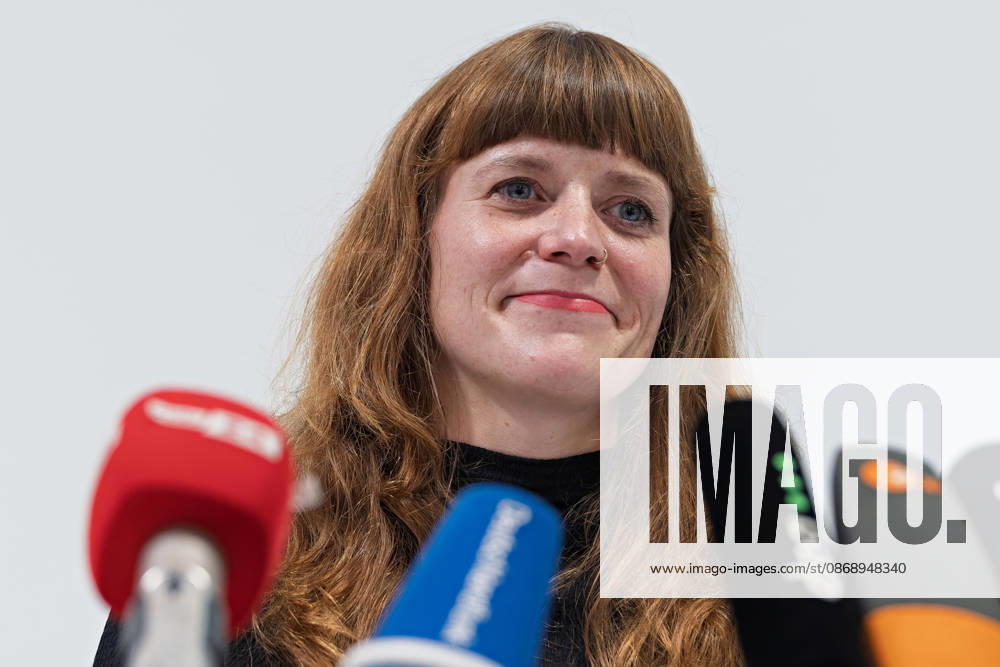 Kerstin Wolter Ehling A member of Die Linke smiles during a joint press statement by Die Linke Berlin, Alliance 90 The Greens Berlin, and the SPD Berlin following the conclusion of preliminary talks in the foyer of the Haus der Statistik, standing behind the media microphones. Joint press statement by The Left, The Greens, and the SPD in Berlin