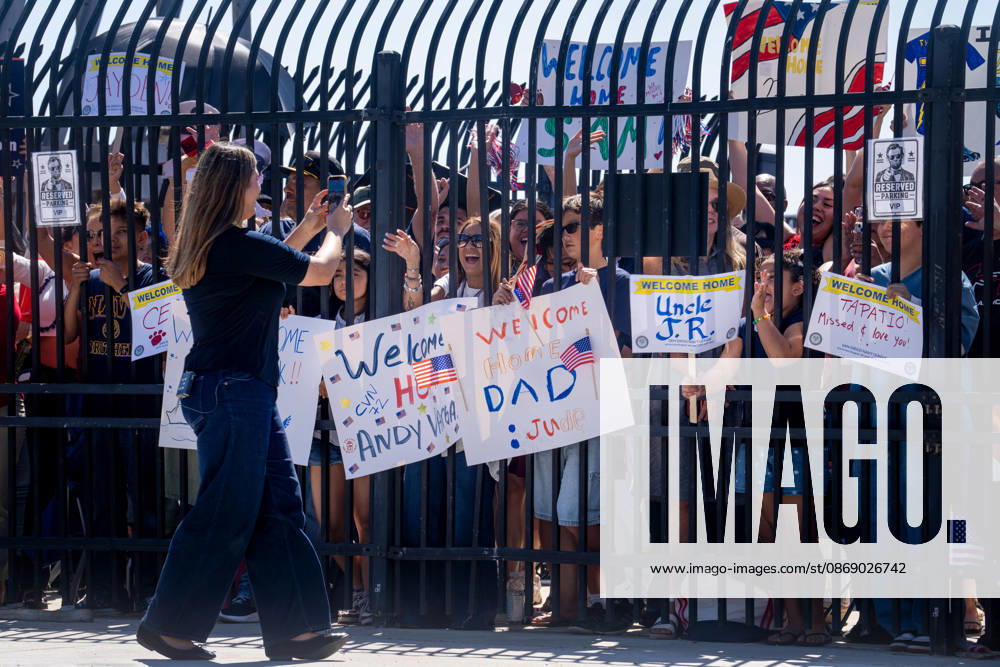 Family members and supporters gather behind a gate holding welcome-home signs as the aircraft carrier USS Abraham Lincoln (CVN 72) returns to Naval Air Station North Island in Coronado, California, on October 8, 2026, following a deployment. Coronado United States - ZUMAg374 20261008_znp_g374_006