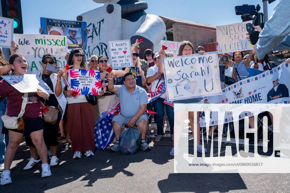 Family members and supporters hold handmade signs and banners welcoming sailors home as the aircraft carrier USS Abraham Lincoln (CVN 72) returns to Naval Air Station North Island in Coronado, California, on October 8, 2026, following a deployment. The signs include personal messages for sailors, including one reading Welcome Home Sarah! and a banner welcoming Aean Ramirez. Coronado United States - ZUMAg374 20261008_znp_g374_014