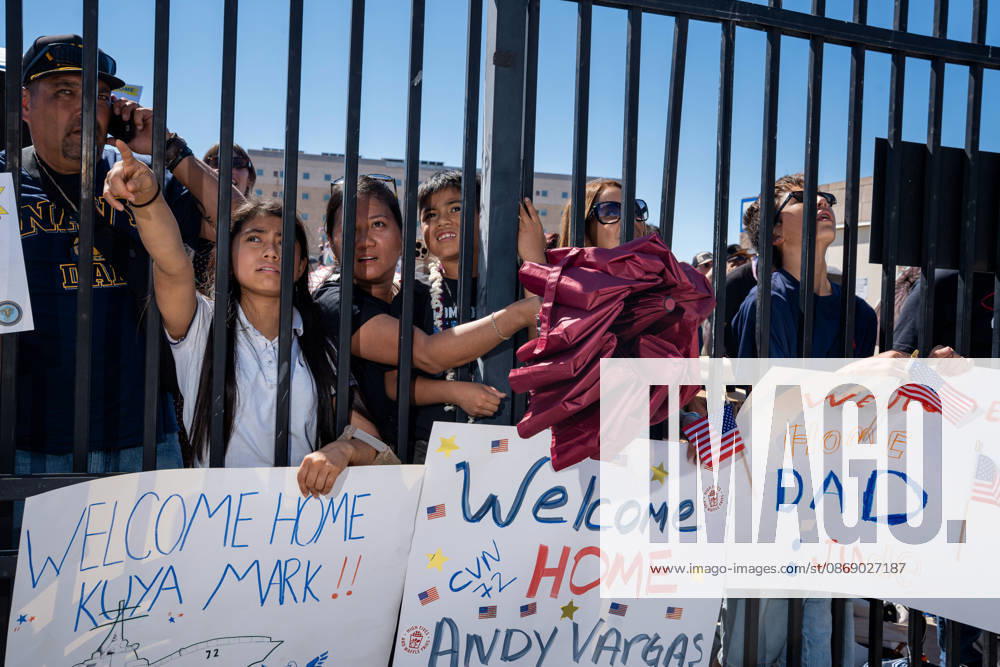 Family members and supporters hold handmade welcome-home signs and wave American flags as they await the return of the aircraft carrier USS Abraham Lincoln (CVN 72) at Naval Air Station North Island in Coronado, California, on October 8, 2026, following a deployment. Coronado United States - ZUMAg374 20261008_znp_g374_023