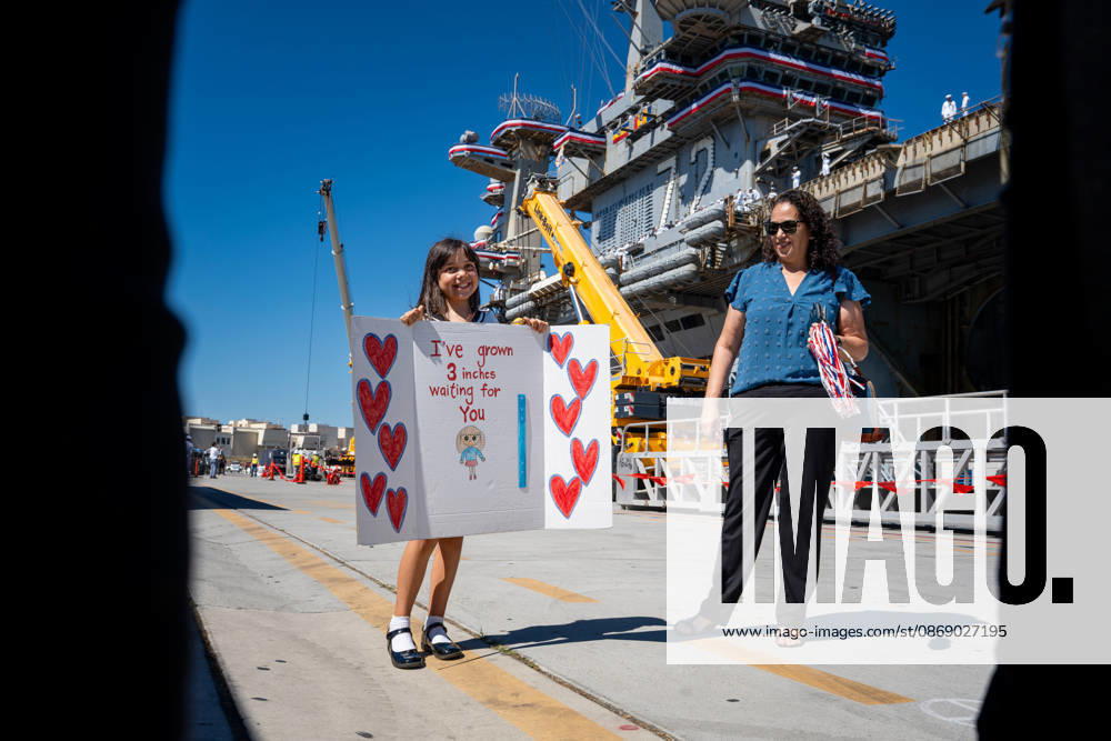 A young girl holds a handmade sign reading Ã¢â‚¬oeI ve grown 3 inches waiting for youÃ¢â‚¬Â alongside a family member as they await the return of the aircraft carrier USS Abraham Lincoln (CVN 72) at Naval Air Station North Island in Coronado, California, on October 8, 2026, following a deployment. Coronado United States - ZUMAg374 20261008_znp_g374_025