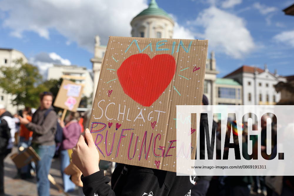 A protester stands in the Alter Markt holding a sign that reads My Heart Beats for Exams during a demonstration calling for the Federal Constitutional Court to review far-right parties, Potsdam, October 10, 2026. Protest demonstration in Potsdam