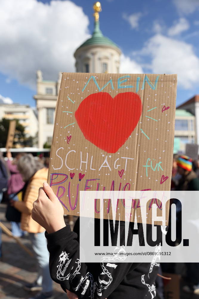 A protester stands in the Alter Markt holding a sign that reads My Heart Beats for Exams during a demonstration calling for the Federal Constitutional Court to review far-right parties, Potsdam, October 10, 2026. Protest demonstration in Potsdam