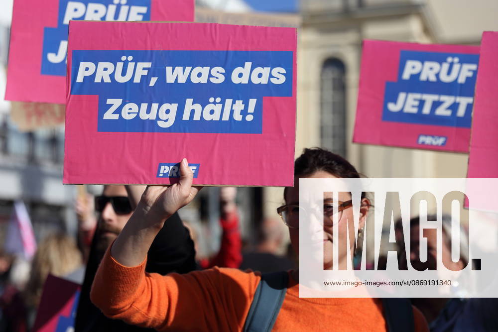 A protester stands on Breite Straße holding a sign that reads Put it to the test during a demonstration calling for the Federal Constitutional Court to review far-right parties, Potsdam, October 10, 2026. Put it to the test demonstration in Potsdam