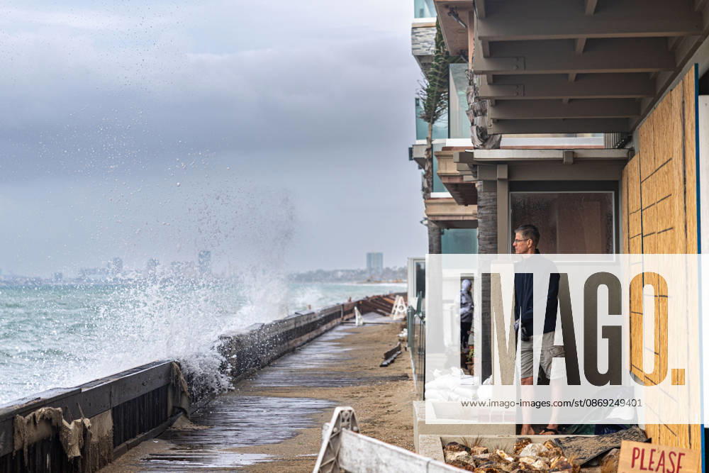 Waves crash into the boardwalk along the Belmont Shore peninsula while a resident watches as remnants of Tropical Storm Rachel make their way through Southern California. Long Beach USA - ZUMAc316 20261011_znp_c316_003