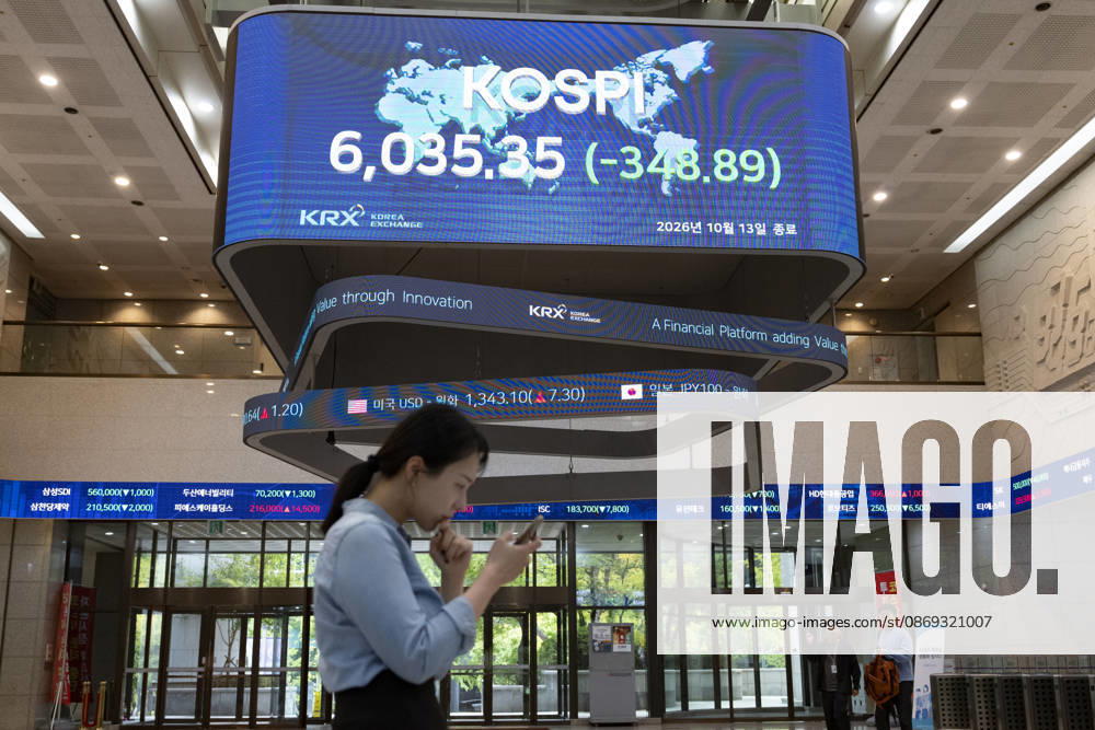 South Korea Stocks Plunge As KOSPI Drops Sharply At KRX In Seoul A Korea Exchange (KRX) employee looks at her smartphone while walking past a display board showing the closing KOSPI index at 6,035.35 (-348.89) in Yeouido, Seoul, South Korea, on October 13, 2026. Seoul Seoul South Korea