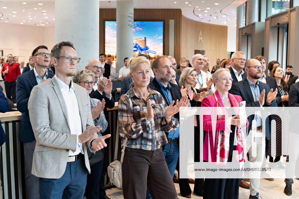 Berlin, 13.10.2026: Gäste applaudieren bei der Eröffnungsfeier im Foyer des neuen DKB-Campus in der Europacity in Berlin-Mitte; im Hintergrund zeigt ein Bildschirm das Motiv der Eröffnungswoche. Die Deutsche Kreditbank AG (DKB) hat ihren neuen Hauptsitz heute offiziell eröffnet. Der von Kleihues + Kleihues entworfene, rund 82 Meter hohe Komplex besteht aus drei Gebäudeteilen mit fünf, elf und 19 Geschossen und rund 35.000 Quadratmetern Mietfläche; entwickelt wurde er von der CA Immo unter dem Projektnamen Upbeat. Rund 2.600 Mitarbeitende des DKB-Konzerns, die bislang auf mehrere Berliner Standorte verteilt waren, arbeiten nun gemeinsam im Campus. Die DKB ist Exklusivmieterin und hat einen Mietvertrag über 15 Jahre abgeschlosse