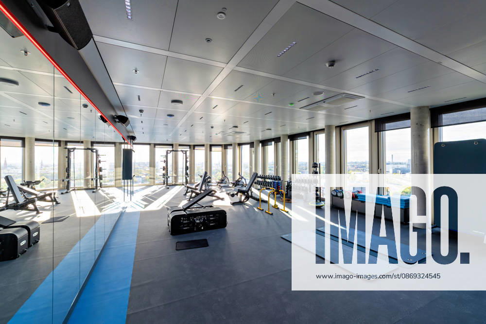 Berlin, 13.10.2026: Fitnessraum mit Hantelbänken, Kurzhanteln und Trainingsmatten im neuen DKB-Campus in der Europacity in Berlin-Mitte; durch die Fensterfront fällt der Blick über die Stadt. Die Deutsche Kreditbank AG (DKB) hat ihren neuen Hauptsitz heute offiziell eröffnet. Der von Kleihues + Kleihues entworfene, rund 82 Meter hohe Komplex besteht aus drei Gebäudeteilen mit fünf, elf und 19 Geschossen und rund 35.000 Quadratmetern Mietfläche; entwickelt wurde er von der CA Immo unter dem Projektnamen Upbeat. Rund 2.600 Mitarbeitende des DKB-Konzerns, die bislang auf mehrere Berliner Standorte verteilt waren, arbeiten nun gemeinsam im Campus. Die DKB ist Exklusivmieterin und hat einen Mietvertrag über 15 Jahre abgeschlossen.