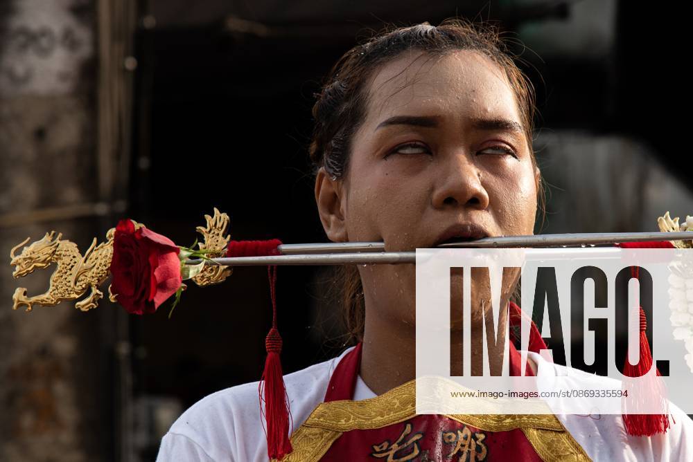 A devotee with a skewer piercing her cheek participates in a street procession during the Vegetarian Festival..The annual Vegetarian Festival is held in Bangkok and many parts of southern Thailand, including Trang, Phatthalung, and Phuket, where worshippers refrain from eating animal products over the nine days, coinciding with the celebration of the Nine Emperor Gods. Trang Thailand - ZUMAs197 20261013_aaa_s197_183