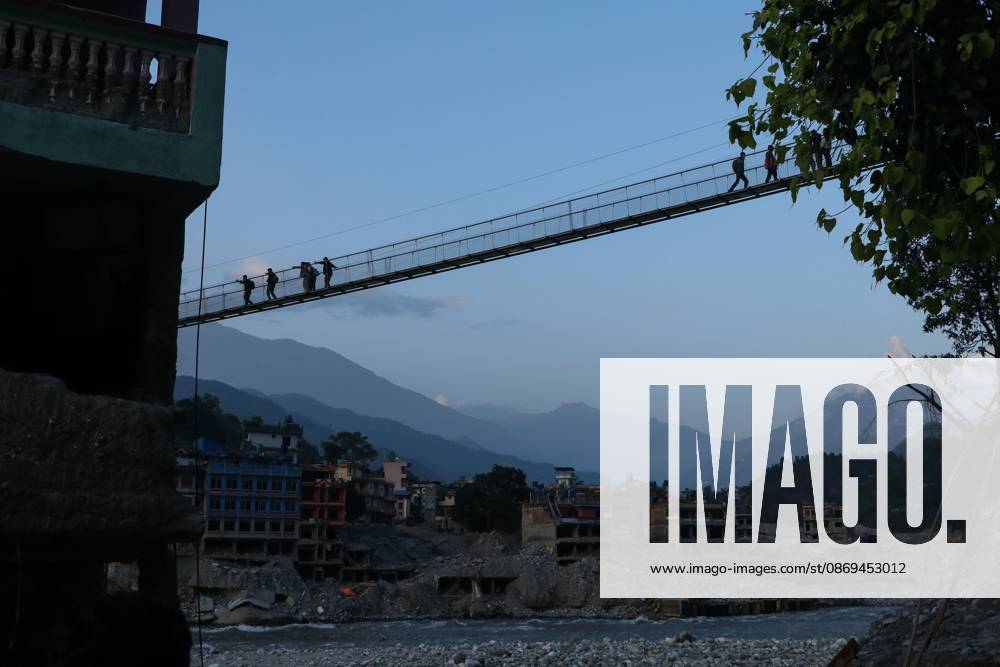 Nepal Bridge Restores Flood-Hit Access NUWAKOT, NEPAL, OCTOBER 14, 2026: Residents cross a newly built suspension bridge over the Trishuli River in Nuwakot, restoring access between communities affected by flash floods. Flooding destroyed bridges and damaged roads in the district, disrupting travel and access to essential services. NUWAKOT Nepal
