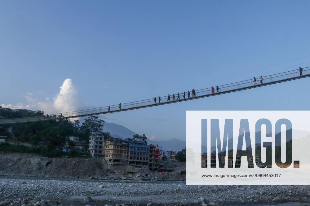 Nepal Bridge Restores Flood-Hit Access NUWAKOT, NEPAL, OCTOBER 14, 2026: Residents cross a newly built suspension bridge over the Trishuli River in Nuwakot, restoring access between communities affected by flash floods. Flooding destroyed bridges and damaged roads in the district, disrupting travel and access to essential services. NUWAKOT Nepal