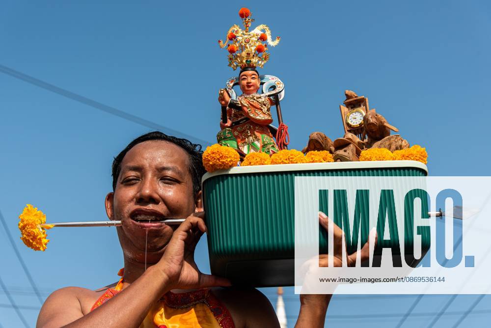 A devotee with a skewer piercing his cheek participates in a street procession during the Vegetarian Festival..The annual Vegetarian Festival is held in Bangkok and many parts of southern Thailand, including Trang, Phang Nga, and Phuket, where worshippers refrain from eating animal products over the nine days, coinciding with the celebration of the Nine Emperor Gods. Trang Thailand - ZUMAs197 20261015_aaa_s197_007