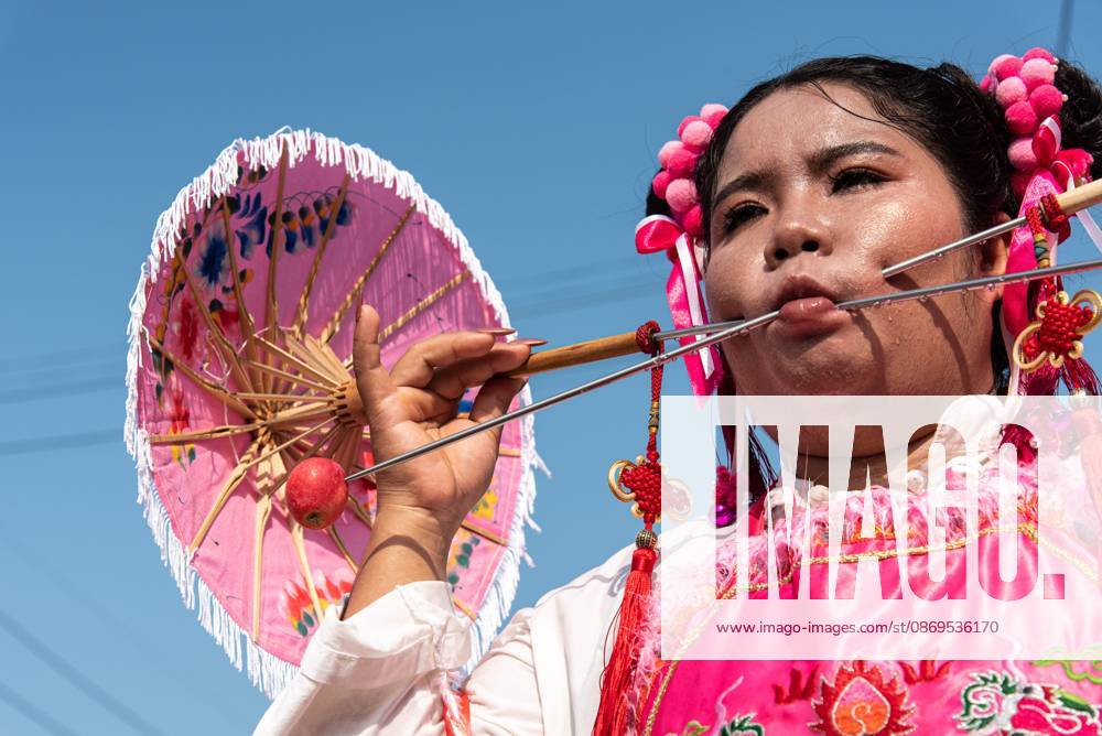 A devotee with a skewer piercing her cheek participates in a street procession during the Vegetarian Festival..The annual Vegetarian Festival is held in Bangkok and many parts of southern Thailand, including Trang, Phang Nga, and Phuket, where worshippers refrain from eating animal products over the nine days, coinciding with the celebration of the Nine Emperor Gods. Trang Thailand - ZUMAs197 20261015_aaa_s197_009