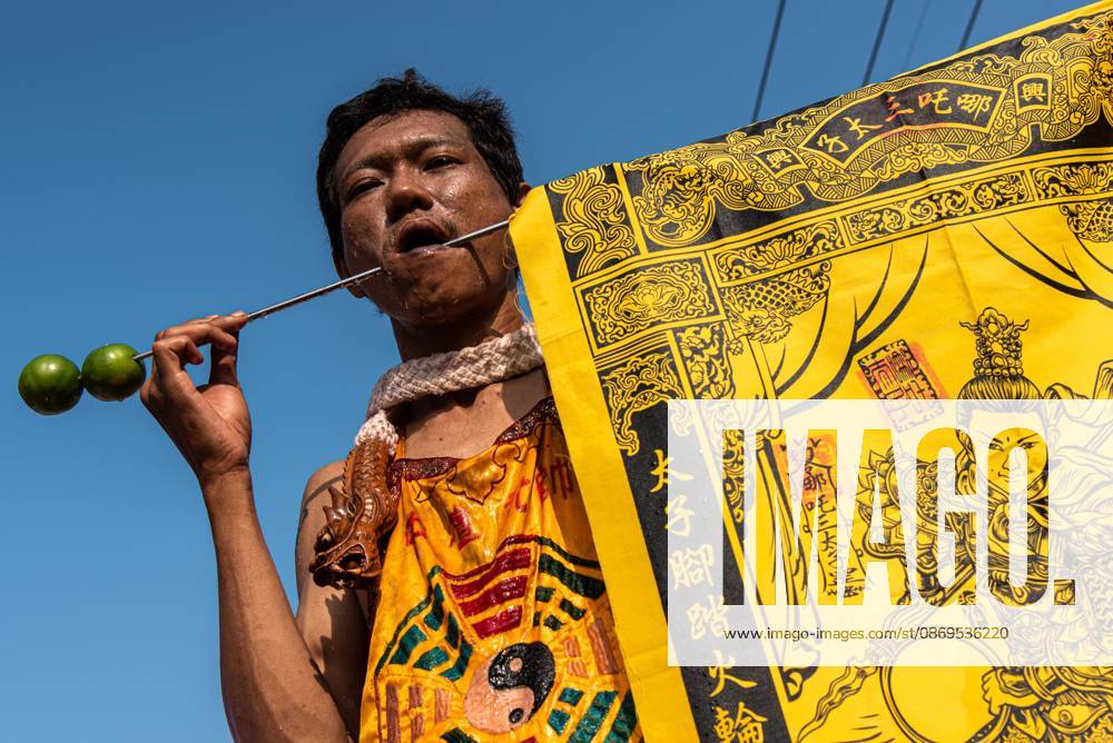 A devotee with a skewer piercing his cheek participates in a street procession during the Vegetarian Festival..The annual Vegetarian Festival is held in Bangkok and many parts of southern Thailand, including Trang, Phang Nga, and Phuket, where worshippers refrain from eating animal products over the nine days, coinciding with the celebration of the Nine Emperor Gods. Trang Thailand - ZUMAs197 20261015_aaa_s197_018