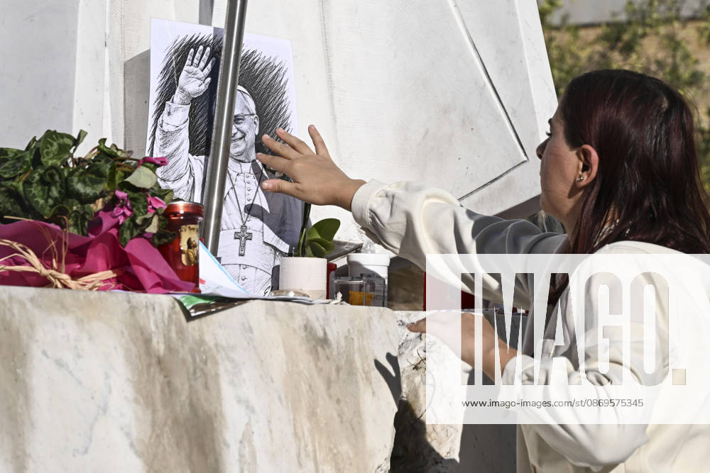 A girl, author of the drawing, places a portrait of Pope Leo at the foot of the statue of Pope John Paul II outside Agostino Gemelli University Hospital, where Pope Leo XIV is hospitalized, Rome, Italy, 15 October 2026. According to the Holy See Press Office, Pope Leo XIV is recovering after undergoing successful surgery on 13 October to remove the lower lobe of his right lung. Doctors confirmed a diagnosis of lung adenocarcinoma during the operation. ANSA RICCARDO ANTIMIANI. Rome Italy - ZUMAa110 20261015_zaf_a110_016