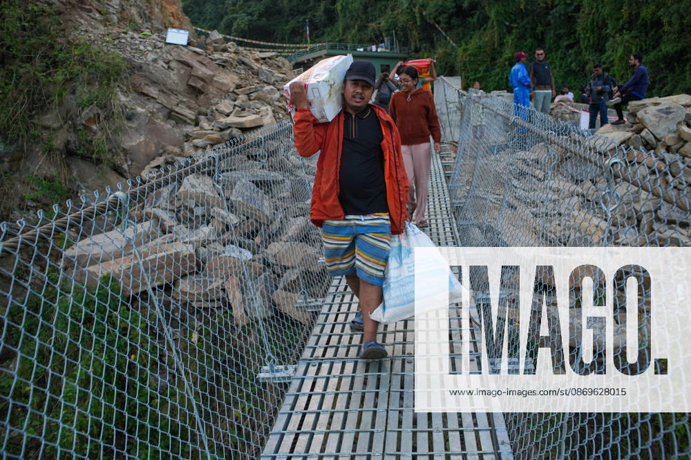 Local residents carry supplies while preparing to cross the newly installed Bailey bridge connecting the border areas of Nuwakot and Rasuwa districts on October 15, 2026 in Nuwakot, Nepal. The bridge was installed to restore road connectivity after severe flooding destroyed existing bridges on August 26, 2026.
