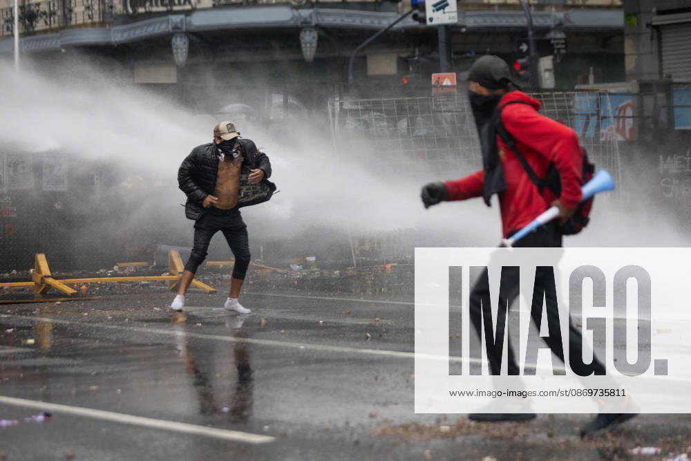 Protesters flee water sprayed from police water cannon trucks during clashes with police. Buenos Aires Argentina - ZUMAp265 20261016_zip_p265_048