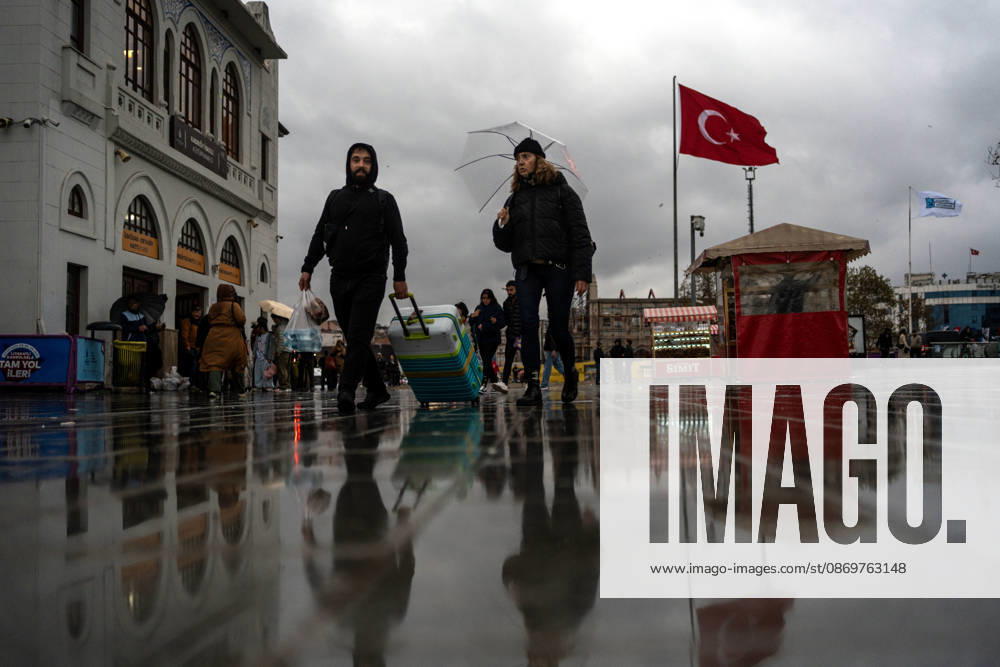 People pull luggage across a wet square beneath Turkish flags in Istanbul, Turkey. Istanbul faces another round of heavy rain after floods that left five people dead, with orange alerts in place and downpours expected to intensify, according to ToÂ¼rkiye Today. Istanbul Turkey - ZUMAz174 20261017_zip_z174_005