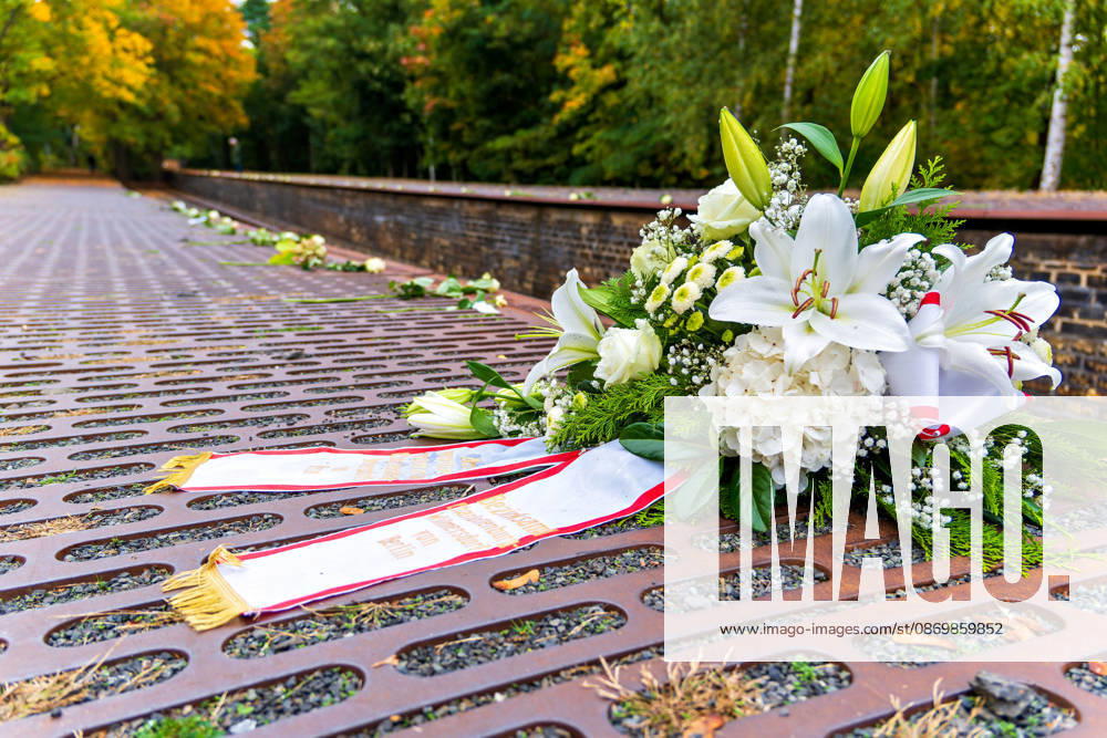 Berlin-Grunewald, 18.10.2026: Ein Gesteck mit weißen Lilien und Hortensien des Bezirks Charlottenburg-Wilmersdorf liegt nach der Gedenkveranstaltung zum 85. Jahrestag des Beginns der nationalsozialistischen Deportationen von Jüdinnen und Juden aus Berlin auf den Stahlplatten des Mahnmals Gleis 17; dahinter sind entlang der Bahnsteigkante weiße Rosen abgelegt. Das Mahnmal Gleis 17 am Bahnhof Grunewald erinnert an die Deportation von mehr als 50.000 Berliner Jüdinnen und Juden; der erste Zug fuhr am 18. Oktober 1941 in das Ghetto Litzmannstadt (Å?odÅº). 186 Stahlgussplatten entlang der Gleiskanten verzeichnen chronologisch jeden Transport mit Datum, Zahl der Deportierten und Zielort, bis zum letzten Zug am 5. Januar 1945 nach Sachsenhaus