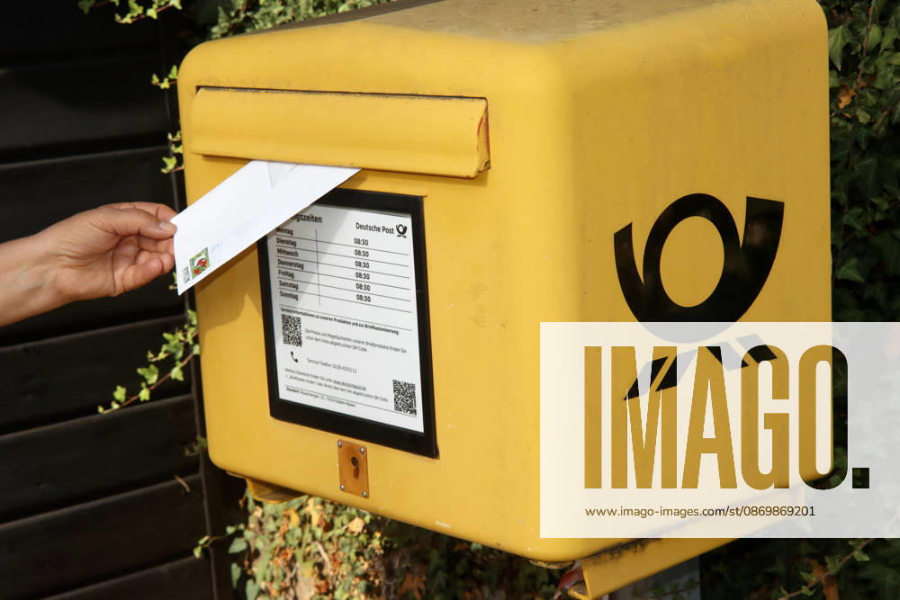 A Woman throws a Brief in the yellow Mailbox 1033004986